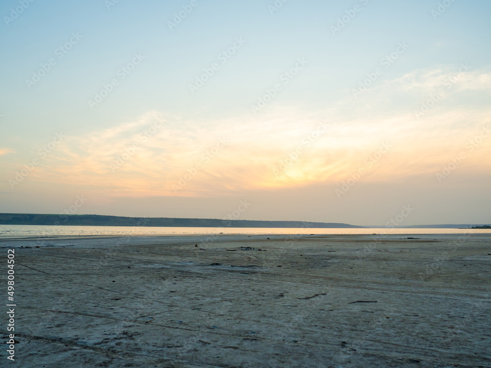 Dried up sandy estuary under the boundless sky. Twilight on the salt lake beach. Dried up sandy estuary under the boundless sky. Twilight on the salt lake beach.