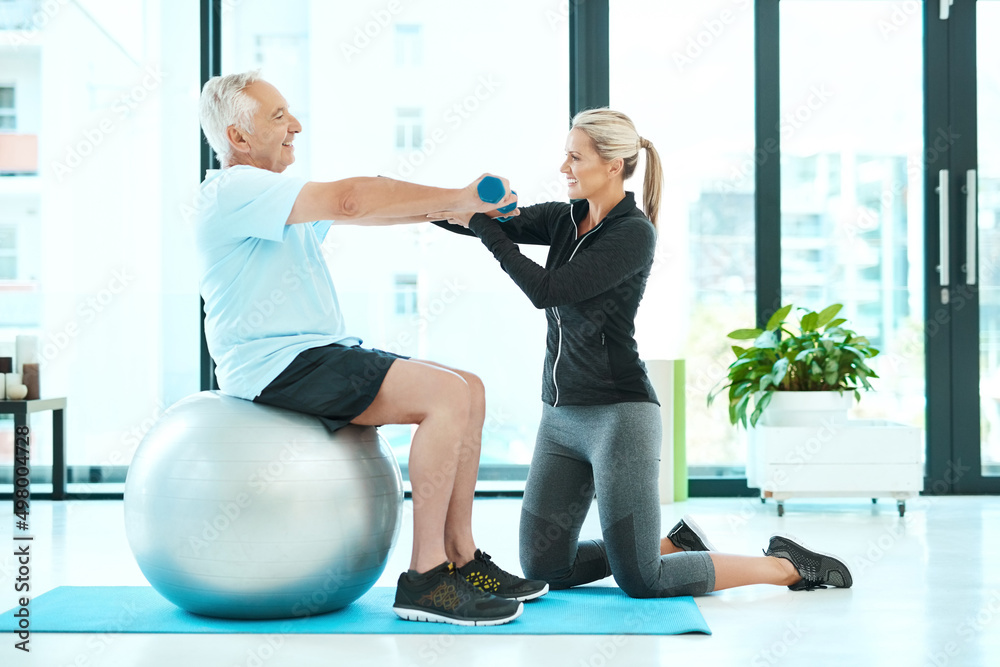 Fototapeta premium Working on all those stiff muscles. Shot of a physiotherapists helping her senior patient with his exercises in a fitness center.