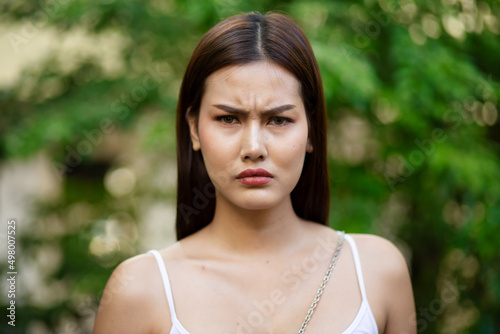 Face of frowning angry upset asian woman in summer park photo