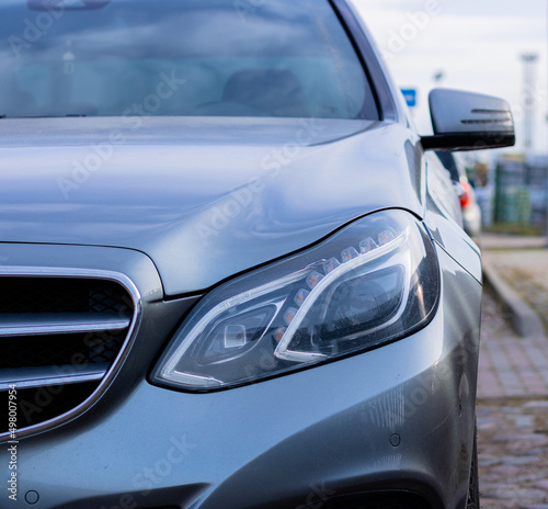 Car front light. Gray Luxury Car Front Headlight View in a Parking Space. Car in the Street.