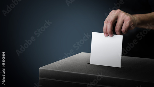 Dark side ballot box with hand person vote on blank voting slip at dark background..