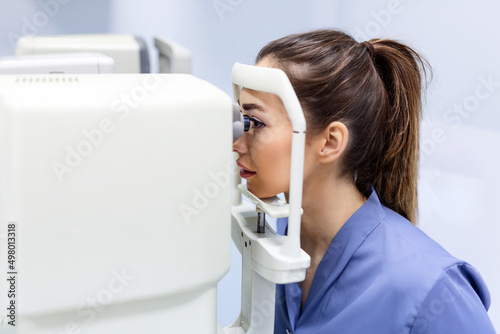 Doctor testing for eyes with special optical apparatus in modern clinic. Ophthalmologist examining eyes of a patient using digital microscope during a medical examination in the ophthalmologic office