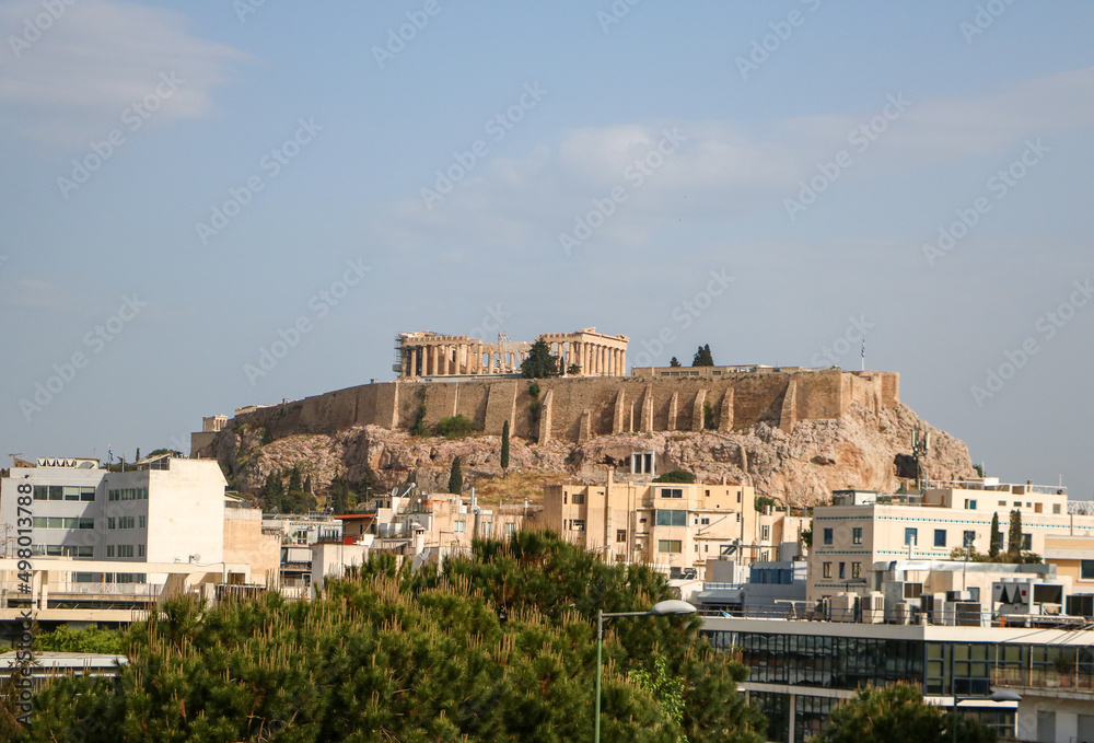 The Parthenon on the Acropolis of Athens in Greece from a distance with some buildings in the foreground.