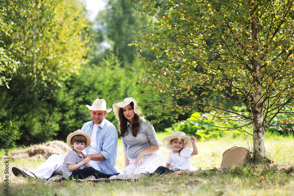 Happy family with children having picnic in park, parents with kids sitting on garden grass and eating watermelon outdoors Happy family with children having picnic in park, parents with kids sitting on garden grass and eating watermelon outdoors