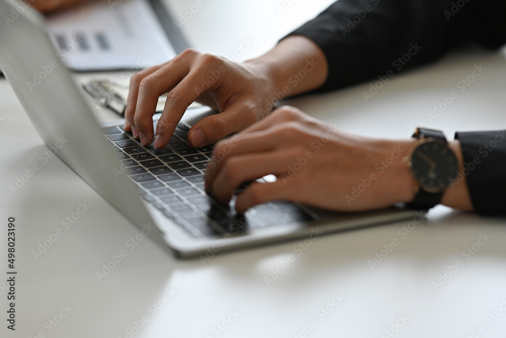 Cropped view businessman sitting in the office and working on a laptop and a document, for business and technology concept. Cropped view businessman sitting in the office and working on a laptop and a document, for business and technology concept.
