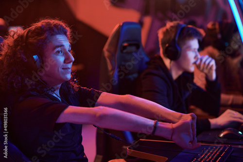 Content young Caucasian computer gamer with long curly hair stretching fingers before esports competition