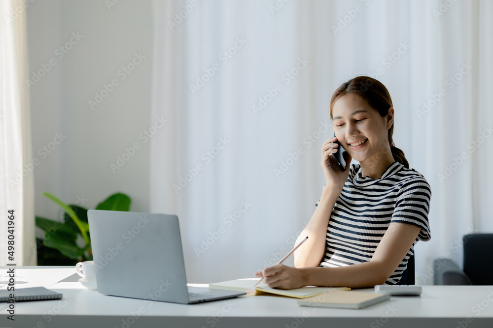 Woman talking on the phone with a friend after finishing one online class, she is a university student studying online due to the COVID-19 pandemic. Online learning to reduce the epidemic concept. Woman talking on the phone with a friend after finishing one online class, she is a university student studying online due to the COVID-19 pandemic. Online learning to reduce the epidemic concept.