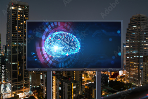 Brain hologram on billboard with Bangkok cityscape background at night time. Street advertising poster. Front view. The largest science hub in Southeast Asia. Coding and high-tech science.