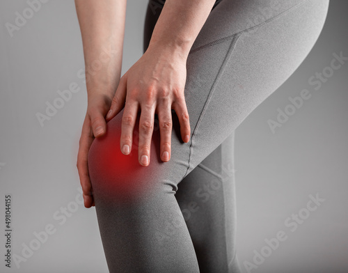 Knee pain. Woman holding painful leg with red spot closeup. Arthritis, tendonitis, sprained or strained ligaments consequences. Health care, orthopedic problems and medicine concept. photo