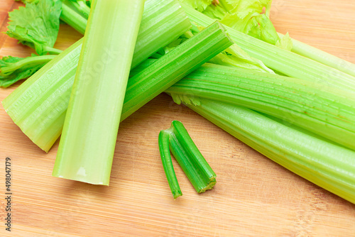 Fresh Celery Stem and Chopped Celery Sticks on Wooden Cutting Board. Vegan and Vegetarian Culture. Raw Food. Healthy Diet with Negative Calorie Content. Slimming Food