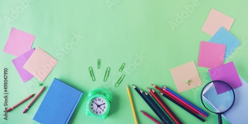 Alarm clock, Art materials and stationery on a green background, top view, back to school, holidays, education and training