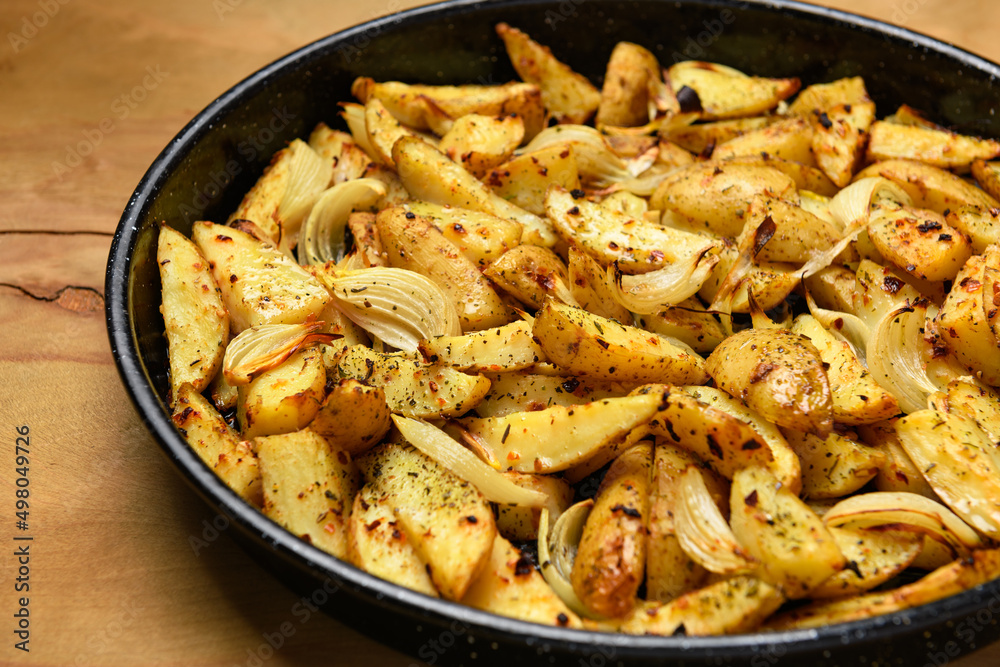 roasted potatoes in a frying pan, cooked food, delicious crust, one object on a wooden background