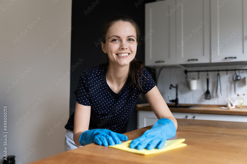Woman wear rubber gloves cleaning kitchen counter use soft rag smile staring at camera look happy enjoy domestic chores alone at home. House cleaning services worker portrait, household work concept Woman wear rubber gloves cleaning kitchen counter use soft rag smile staring at camera look happy enjoy domestic chores alone at home. House cleaning services worker portrait, household work concept