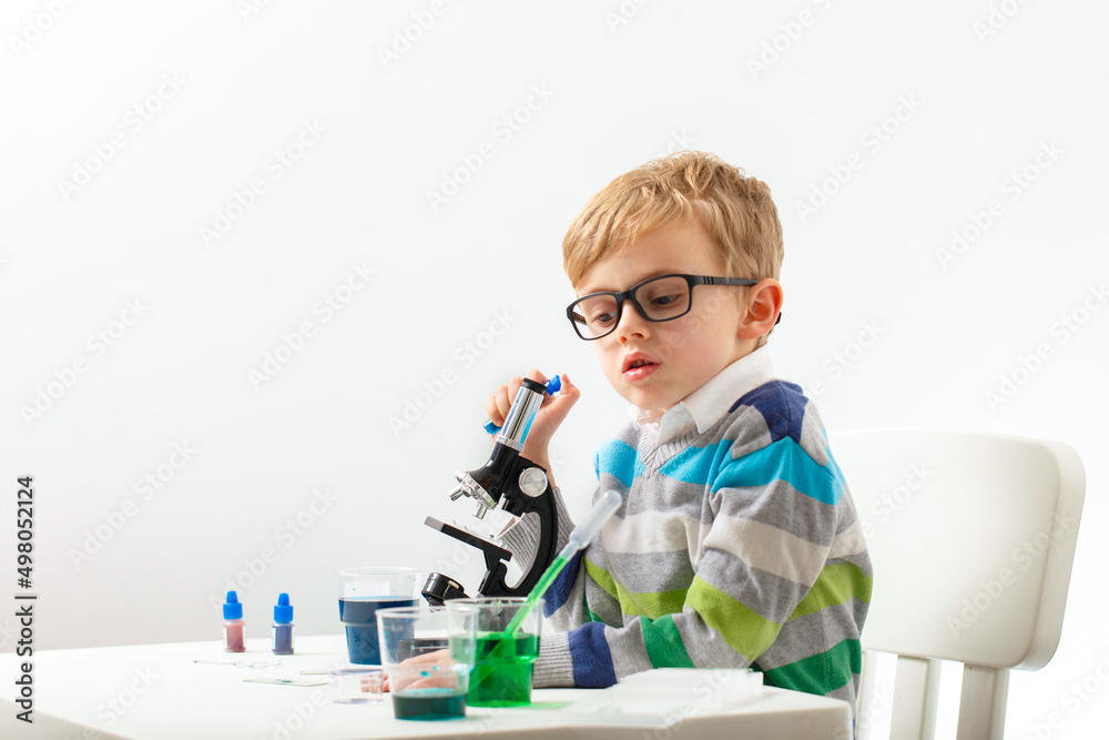 Boy five years old, experimenting with colored liquids. Chemical experiments of a little scientist boy of European appearance. Boy five years old, experimenting with colored liquids. Chemical experiments of a little scientist boy of European appearance.