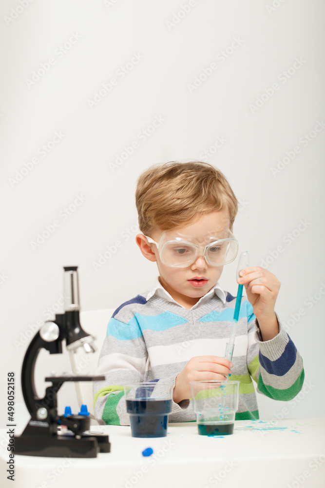 Boy five years old, experimenting with colored liquids. Chemical experiments of a little scientist boy of European appearance. Boy five years old, experimenting with colored liquids. Chemical experiments of a little scientist boy of European appearance.