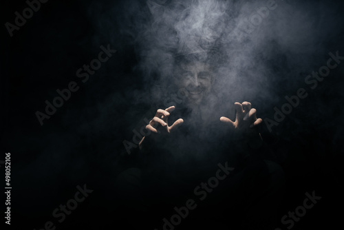 Fototapeta Naklejka Na Ścianę i Meble -  smoke clouds arround man with a hat on dark background