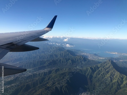 shot from inside the plane. Top view of forest and wing of airplane in pacific. Flight and vacation concept