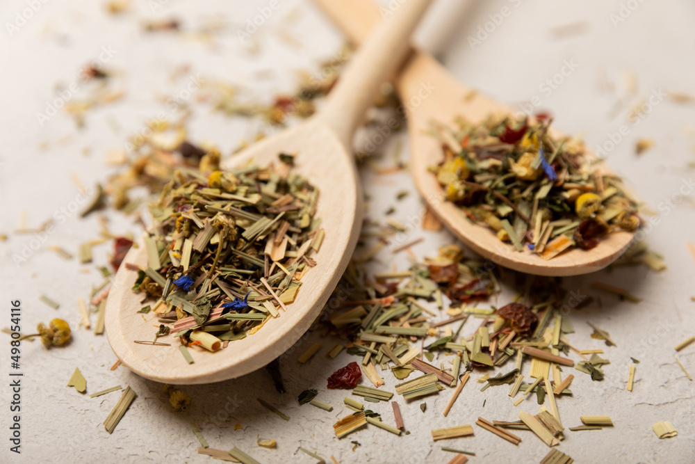 Dry herbal tea in wooden spoons on a gray cement background.Top view.Children and immunity tea.Copy space. Place for text.