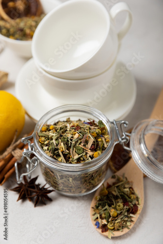 Aromatic herbal tea in a glass jar on a light gray background. Tea set with lemon, cinnamon, ginger and anise. Immune and vitamin tea. Cold drink. side view.