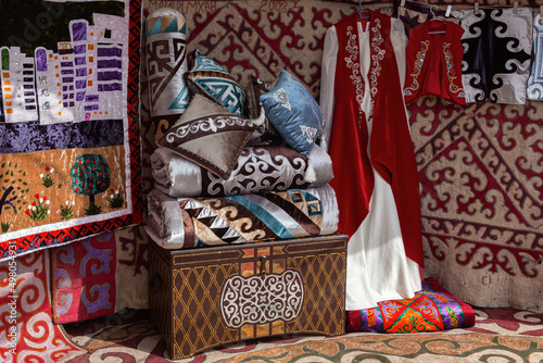 Interior decoration of a traditional nomad house yurt - a chest, pillows and blankets, felt carpets, national clothes photo