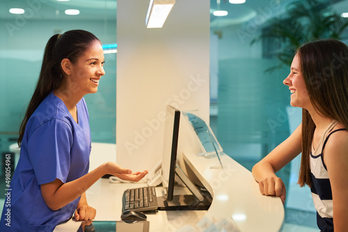 Are you here for a checkup. Shot of a young nurse assisting a patient at the reception desk.