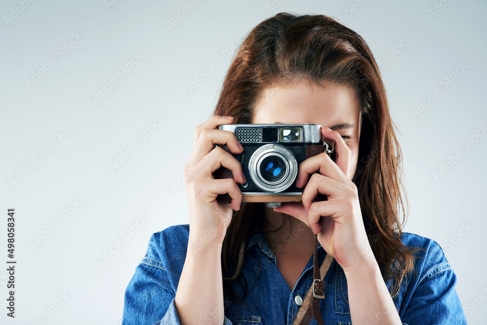 Retro is the way to go. Studio portrait of a young woman using a vintage camera against a grey background. Retro is the way to go. Studio portrait of a young woman using a vintage camera against a grey background.
