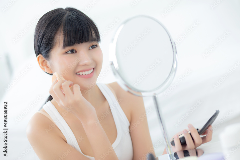Beautiful young asian woman applying powder puff on cheek makeup of cosmetic looking mirror, beauty of girl with skin face and wrinkle in the bedroom, cosmetology for female, skincare concept. Beautiful young asian woman applying powder puff on cheek makeup of cosmetic looking mirror, beauty of girl with skin face and wrinkle in the bedroom, cosmetology for female, skincare concept.
