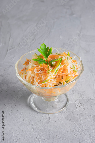 Chinese traditional salad with funchose rice noodles and carrots, cucumbers on a gray biton background photo