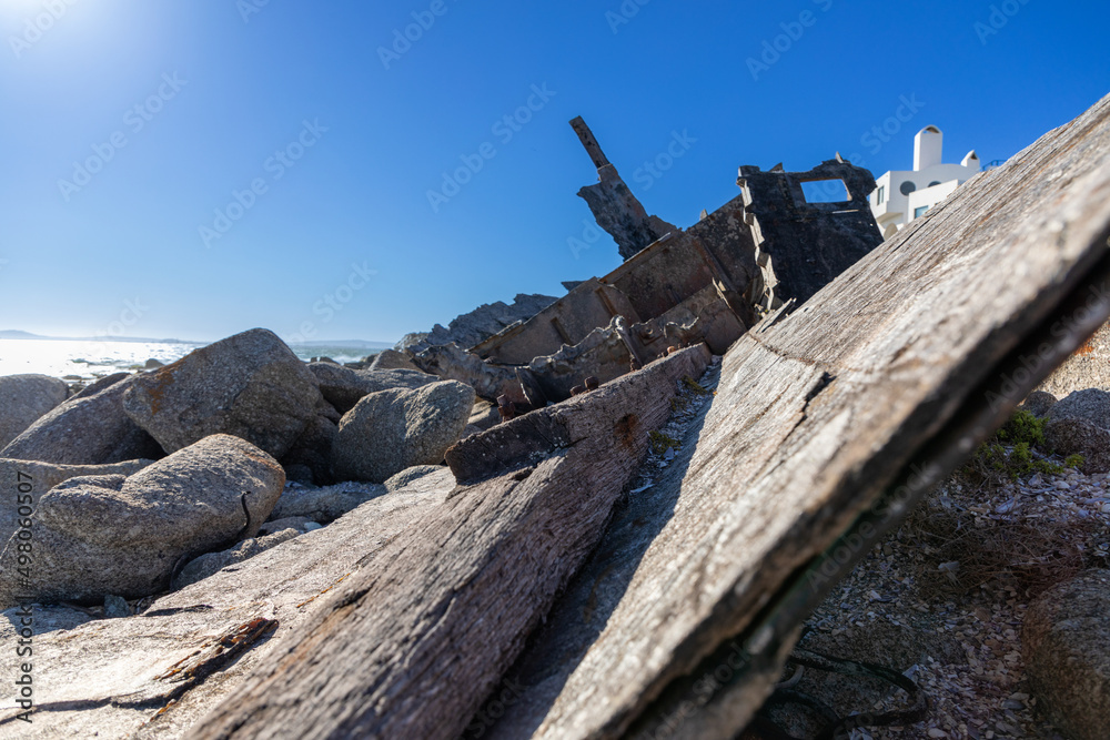 Wooden disintegrating hull of of shipwrecked boat next to rocks. 