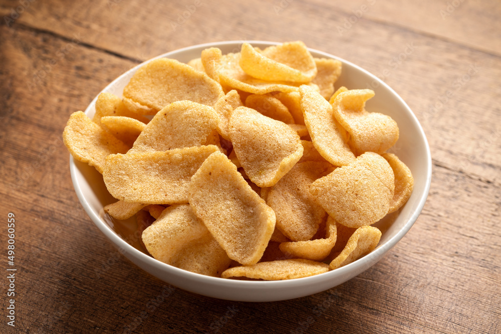 Crispy Prawn Crackers in white bowl on wooden table Crispy Prawn Crackers in white bowl on wooden table