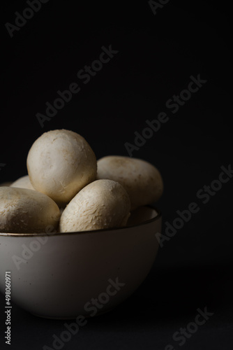 Champignon mushrooms in a plate on a dark background  ready for cooking.