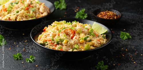 Prawn fried rice with eggs and vegetables in black bowl. Healthy asian food.