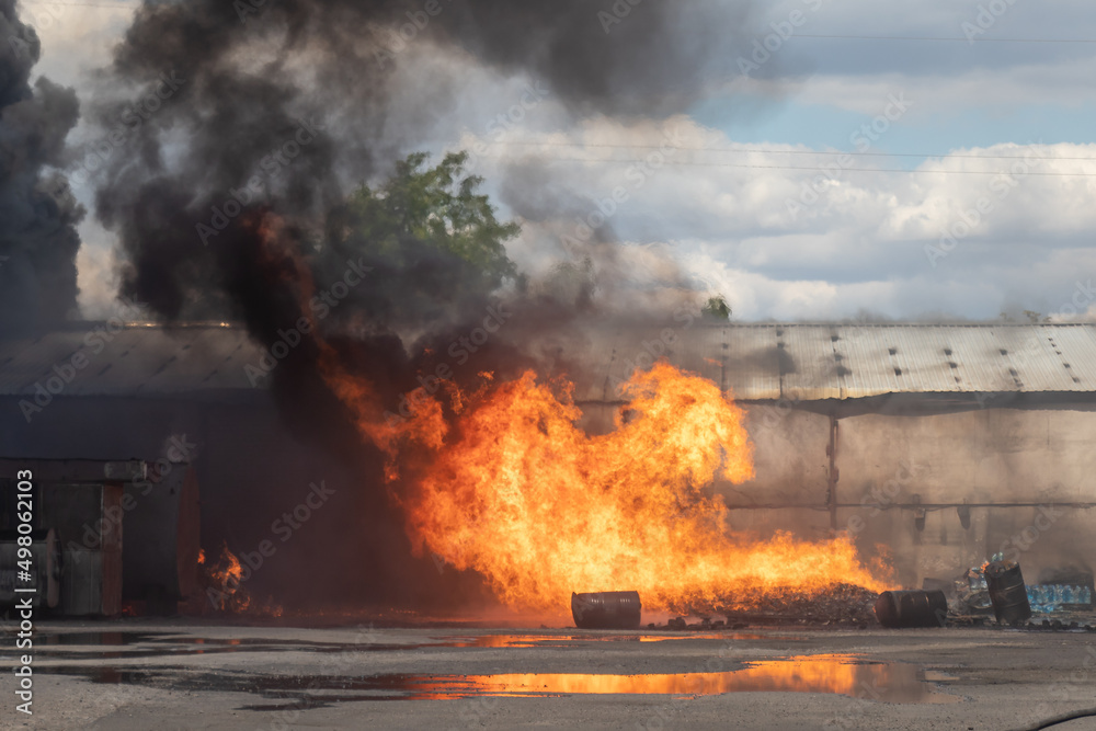Strong fire in the warehouse. Rescuers put out a strong fire. Open fire on the street. hot sunny day Strong fire in the warehouse. Rescuers put out a strong fire. Open fire on the street. hot sunny day