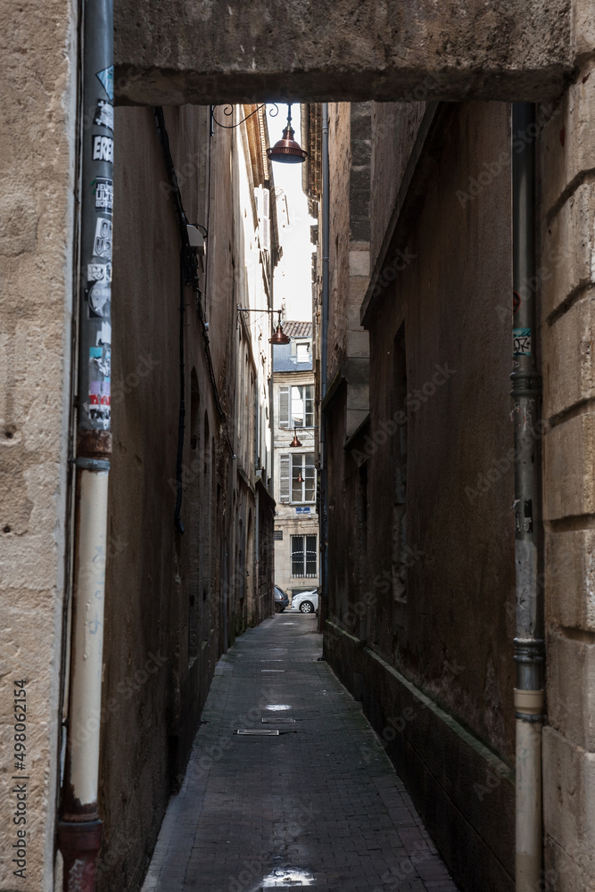 BORDEAUX, FRANCE - FEBRUARY 19, 2022:  Facade of medieval buildings in a dark street, narrow, in city center of Bordeaux, France. These buildings are typical of the Southwestern French architecture