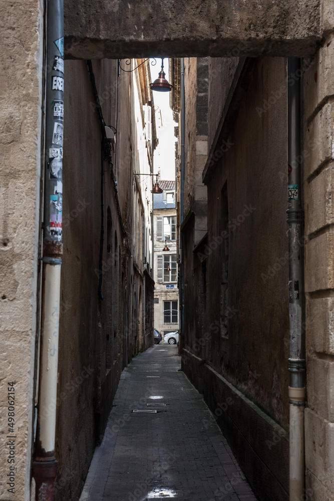 BORDEAUX, FRANCE - FEBRUARY 19, 2022: Facade of medieval buildings in a dark street, narrow, in city center of Bordeaux, France. These buildings are typical of the Southwestern French architecture BORDEAUX, FRANCE - FEBRUARY 19, 2022: Facade of medieval buildings in a dark street, narrow, in city center of Bordeaux, France. These buildings are typical of the Southwestern French architecture