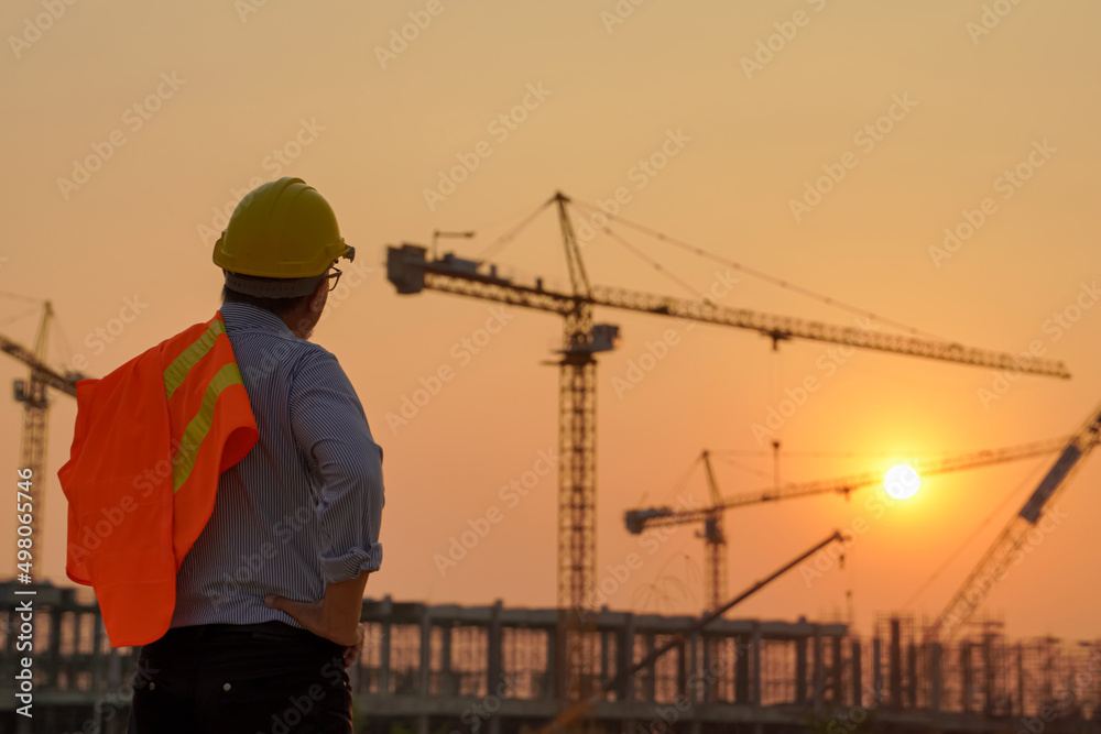 Silhouettes of engineers and workers working at a real estate project site in an industrial building. Preparing to finish work in the evening Silhouettes of engineers and workers working at a real estate project site in an industrial building. Preparing to finish work in the evening