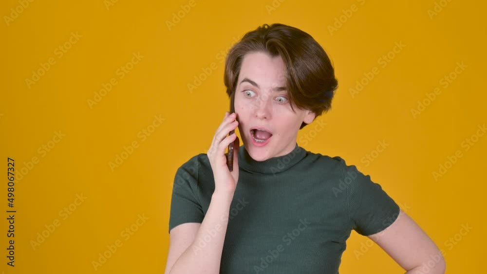 Young girl communicates on the phone, smiles and laughs isolated on a yellow background. Closeup smiling lady talking smartphone. People sincere emotions lifestyle concept. Young girl communicates on the phone, smiles and laughs isolated on a yellow background. Closeup smiling lady talking smartphone. People sincere emotions lifestyle concept.