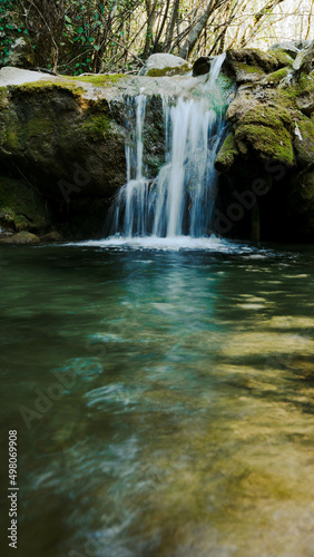 A small mountain waterfall on the river in a picturesque place with moss and trees