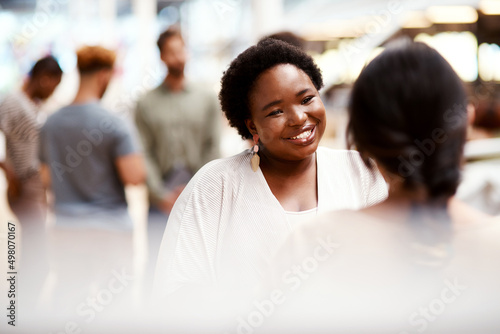 How has your day been going. Shot of a young businesswoman having a discussion with a colleague in an office. photo