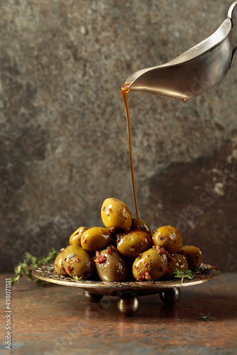 Spicy green olives are poured with olive oil with spices.