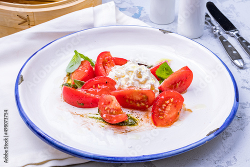 Salad with buratta cheese and tomatoes on bowl on grey table
