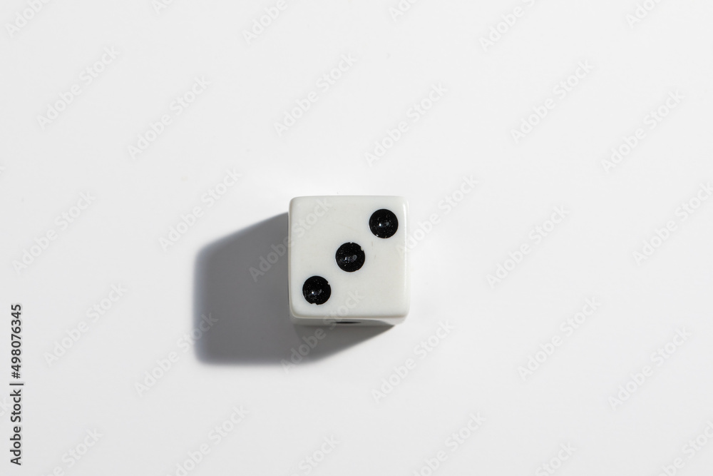 Single white dice with a three on a white background. Win or lose. Catch your luck. Gambling equipment. Single white dice with a three on a white background. Win or lose. Catch your luck. Gambling equipment.