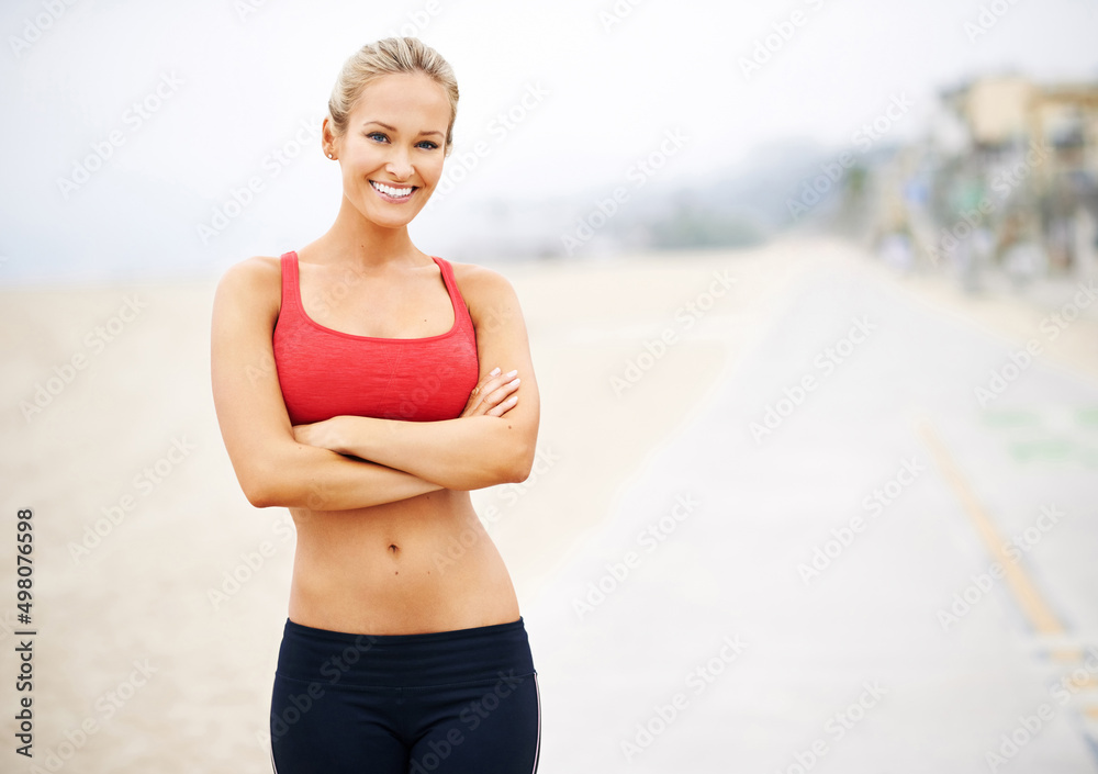 Looking good and feeling amazing. Portrait of a young woman in sportswear standing at the beach. Looking good and feeling amazing. Portrait of a young woman in sportswear standing at the beach.