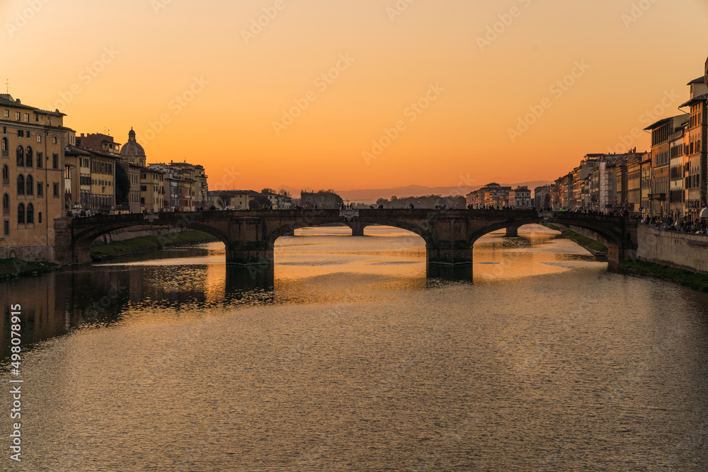 view of a bridge in Florence, Italy and sunset over the Arno river 