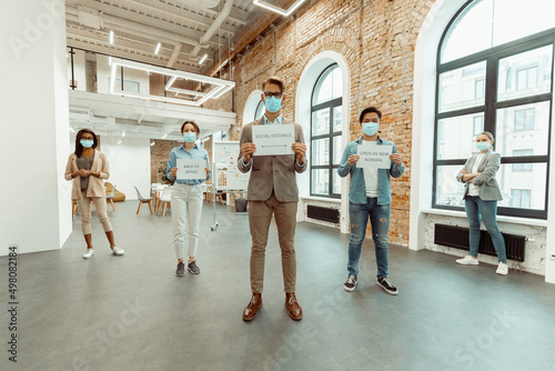 Colleagues in face masks holding sheets of paper with inscriptions