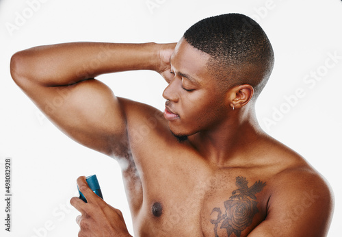 How should a man smell. Studio shot of a handsome young man applying deodorant against a white background.