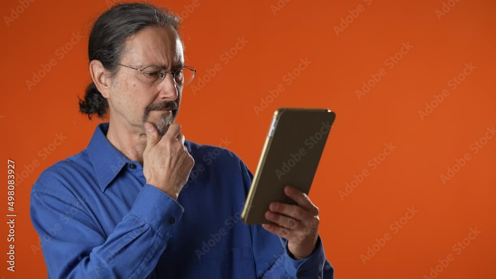 Hipster man in glasses thinking, using digital tablet screen scroll web pages check social network account online. Retired old man spend time concentrating pad computer