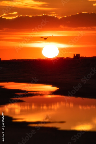 Vibrant orange sunset reflecting in a tidal pool on the beach. Jones Beach, Long Island New York (soft selective focus)