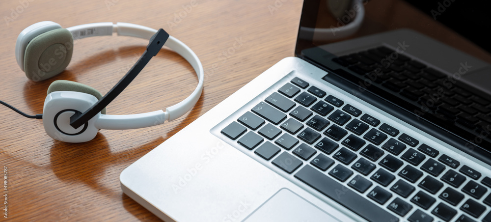 Home office, headset on a laptop, wooden table. Call center, customer support, help desk Home office, headset on a laptop, wooden table. Call center, customer support, help desk
