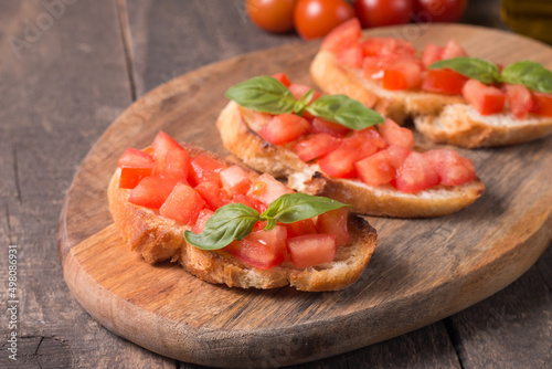 Tomato and basil fresh made bruschetta. Italian tapas, antipasti with vegetables, herbs and oil on grilled ciabatta and baguette bread. Sandwich.